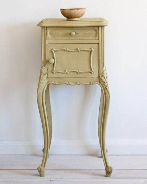 A vintage side table painted in a dark beige chalk paint with a small bowl on top.