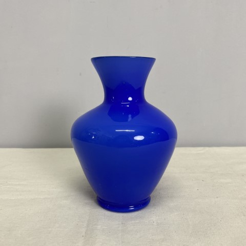 A bright blue glass vase with a curvaceous shape