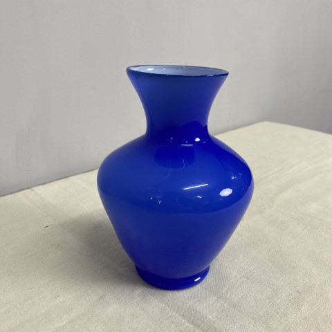 A bright blue glass vase with a curvaceous shape