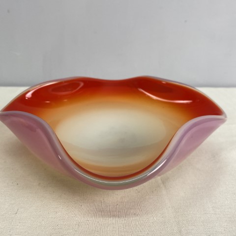 A squared shaped milk glass bowl with orange colouring inside