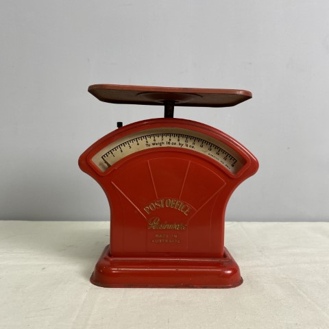 A set of vintage red postal scales with gold writing. Weight scale is in ounces.