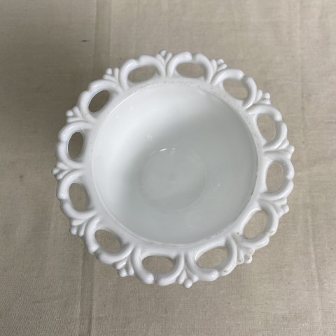 A white milk glass dish with raised decoration and wide rim