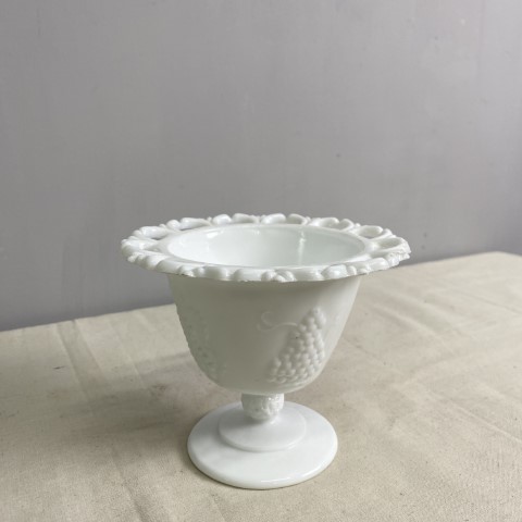 A white milk glass dish with raised decoration and wide rim