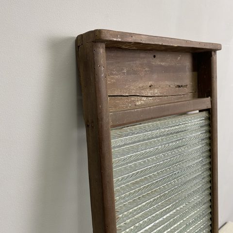 A vintage glass washboard in a rustic timber frame.