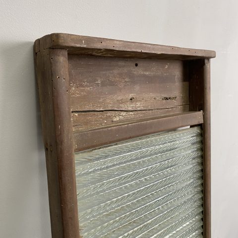 A vintage glass washboard in a rustic timber frame.