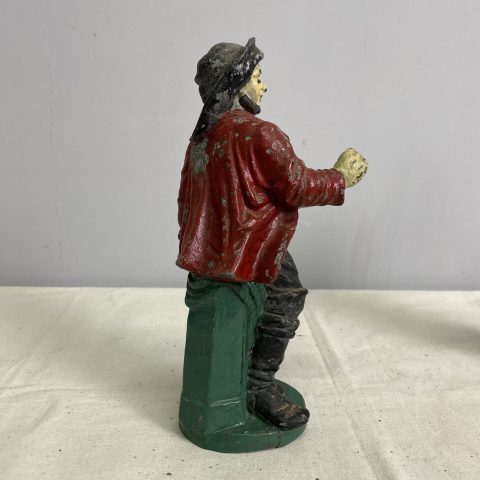 A hand-painted statue of a man leaning on a post wearing a hat and a red jacket