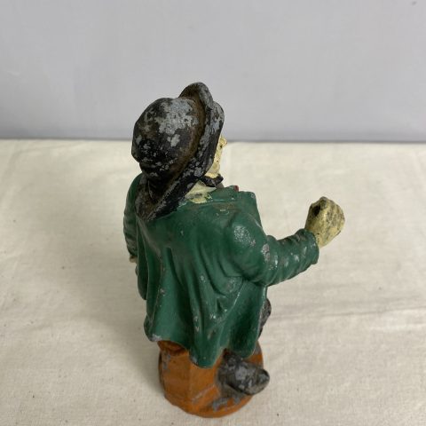 A hand-painted statue of a man leaning on a post wearing a hat and a green jacket