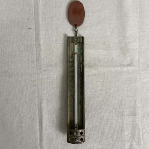 A vintage metal kitchen thermometer