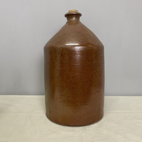A heavy, handmade stoneware bottle in a dark brown colour with a slight speckle under the glaze.