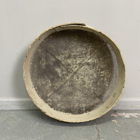 A large round vintage sieve with white wash effect