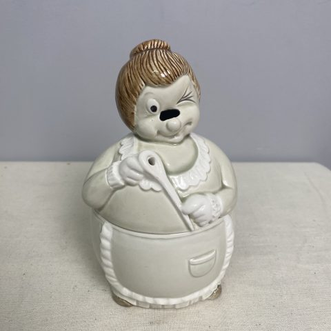 A ceramic twine or string holder in the shape of a woman holding a sewing needle