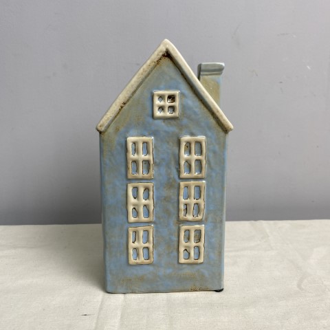 A tall ceramic vase or planter in the shape of a sky blue coloured house