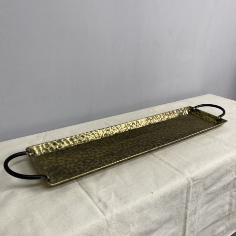 A long narrow gold tray with carry handles and hammered texture
