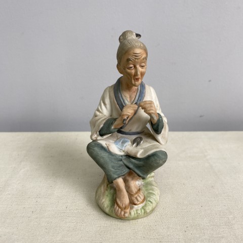 A bisque figure of a lady sitting
