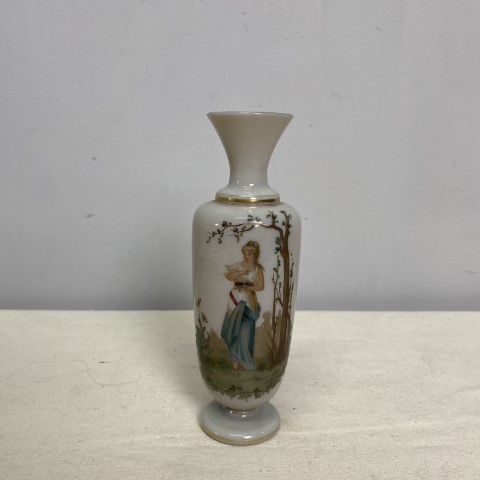 A small, off-white ceramic vase decorated with the image of a painted lady in a toga