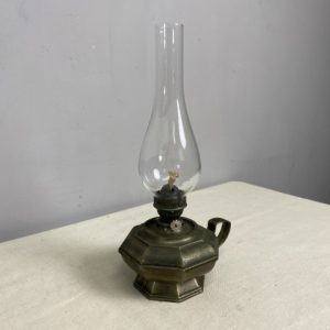 A vintage brass oil lamp with tall glass chimney