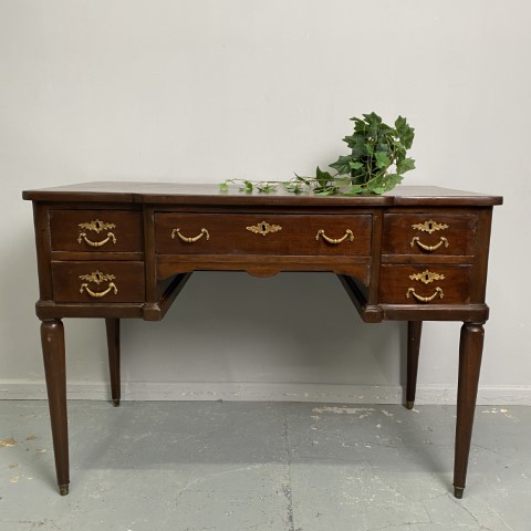 A French style desk with gold handles on the 5 drawers