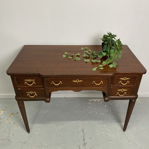 A French style desk with gold handles on the 5 drawers