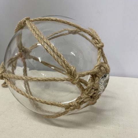 Coastal clear glass buoy wrapped in rope